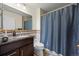 A cozy bathroom with tile, a shower with curtain, a dark vanity, and a modern toilet at 747 Mockingbird St, Brighton, CO 80601