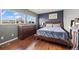 A cozy bedroom with a large window, dark blue wall, wooden furniture, and hardwood floors at 747 Mockingbird St, Brighton, CO 80601