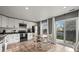 A modern kitchen with white cabinets, stainless steel appliances, and a dining area with a sliding glass door at 747 Mockingbird St, Brighton, CO 80601