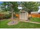 Tan shed with double doors and window, located in a fenced backyard with mature trees at 3131 S Leyden St, Denver, CO 80222