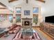 Cozy living room featuring exposed beams, a stone fireplace, and large windows at 12261 Hosman Ct, Conifer, CO 80433