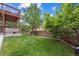 Expansive backyard featuring lush green grass, a wooden fence, and a cozy covered patio area at 10535 Laurelglen Cir, Highlands Ranch, CO 80130