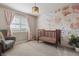 This Bedroom features a crib, gray chair, neutral carpet and flower-print wallpaper at 10535 Laurelglen Cir, Highlands Ranch, CO 80130