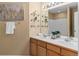 Bathroom featuring double sinks, a large mirror with decorative lighting, and glass display shelves at 9743 Las Colinas Dr, Lone Tree, CO 80124