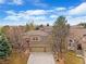 Front exterior view of home with mature trees, large driveway, and two-car garage at 9743 Las Colinas Dr, Lone Tree, CO 80124