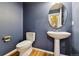 Stylish powder room boasts a pedestal sink, a round mirror, and rich navy walls at 12919 W Burgundy Dr, Littleton, CO 80127