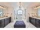 Bright bathroom with double vanity, soaking tub under an arched window, and a tufted ottoman at 15102 Prairie Pl, Broomfield, CO 80023