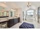 Bright bathroom featuring double vanity with dark cabinets, and a soaking tub under an arched window at 15102 Prairie Pl, Broomfield, CO 80023