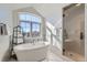 Bright bathroom featuring a soaking tub under an arched window, and a glass-enclosed shower at 15102 Prairie Pl, Broomfield, CO 80023