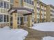 Entrance to apartment building with covered entryway and snow-covered walkway at 750 S Clinton St # 2C, Denver, CO 80247