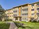 Exterior shot of the tan apartment building with green lawn at 750 S Clinton St # 2C, Denver, CO 80247