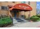 Apartment building entrance under red awning, with trimmed landscaping and steps at 625 N Pennsylvania St # 208, Denver, CO 80203