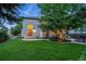 Expansive backyard with a lush lawn, patio, mature trees, and a view of the home's exterior at 505 Orchard Dr, Louisville, CO 80027