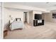 Bright living room featuring neutral walls, carpet, a bed, a TV on a black stand, and an open door at 9271 Wheeler Ct, Highlands Ranch, CO 80126