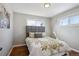 Cozy bedroom featuring hardwood floors, a gray upholstered headboard, and natural light from two windows at 1760 S Yuma St, Denver, CO 80223