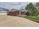 View of a brick home with a long driveway leading to a detached garage at 1325 Elder St, Denver, CO 80221
