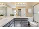 Bright bathroom features double sinks with tile countertops, gray cabinets, and a walk-in shower at 11932 W 56Th Cir, Arvada, CO 80002