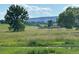 Picturesque landscape view of a field featuring two gazebos and distant mountains at 11932 W 56Th Cir, Arvada, CO 80002