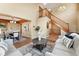 Bright living room view showcasing hardwood floors, staircase, and view into the dining area at 11932 W 56Th Cir, Arvada, CO 80002