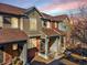 Charming townhouse with a covered front porch, brick accents and colorful sky in the background at 7352 E 7Th Ave # 7, Denver, CO 80230