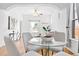 Bright dining room with a glass table, light-colored chairs, and hardwood floors with a view into the living room at 3419 Stuart St, Denver, CO 80212