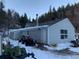 Gray vinyl siding of the house, including an entrance, window, a green four wheeler, and snowy landscaping at 1805 Hidden Valley Rd, Sedalia, CO 80135