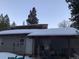 Side exterior of snow-covered house featuring a covered patio and access door at 1805 Hidden Valley Rd, Sedalia, CO 80135