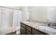 Bathroom featuring double sinks with granite counters, a shower-tub combo, and wood-look floors at 47312 Lilac Ave, Bennett, CO 80102
