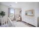 Bedroom featuring natural light, a crib, white dresser, and a comfortable seating chair at 47312 Lilac Ave, Bennett, CO 80102