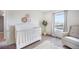 Bedroom featuring a white crib, seating chair, decorative wall art, and a tree at 47312 Lilac Ave, Bennett, CO 80102