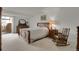 A clean bedroom is decorated with a wood frame bed, dresser, mirror, rocking chair, and light colored carpet at 7000 E Quincy Ave # 302, Denver, CO 80237