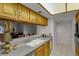 This kitchen features wooden cabinetry, light countertops, white appliances, and a breakfast bar that opens up to another room at 7000 E Quincy Ave # 302, Denver, CO 80237