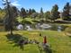 Picturesque pond with fountain surrounded by lush greenery, mature trees, and outdoor seating area at 7000 E Quincy Ave # 302, Denver, CO 80237