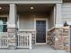 Dark brown front door with stone and white porch railing at 9072 Quintero St, Commerce City, CO 80022