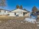 Exterior view of home with a spacious backyard and snow covered grass at 5665 Niagara St, Commerce City, CO 80022