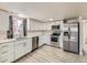 Bright kitchen features stainless appliances, white cabinets, and quartz counters by a sunny window at 5665 Niagara St, Commerce City, CO 80022