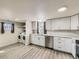 Bright kitchen features white cabinets, stainless steel appliances, light wood floors, and a laundry area at 5665 Niagara St, Commerce City, CO 80022