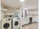 Bright laundry room with machines, shelving, and white cabinets with stainless appliances at 5665 Niagara St, Commerce City, CO 80022