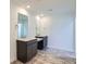 Modern bathroom featuring double vanity sinks with dark cabinets and stone look flooring at 747 Raindance St, Erie, CO 80516