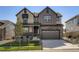 Charming two-story home featuring stone accents, a covered porch, and an attached two-car garage at 747 Raindance St, Erie, CO 80516