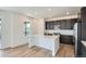 Bright kitchen with white countertops, dark cabinets, a center island, and wood flooring at 747 Raindance St, Erie, CO 80516