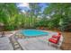 Backyard in-ground pool with diving board, chairs, concrete and stone deck, and mature trees at 629 Bellaire St, Denver, CO 80220