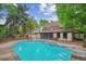 Backyard in-ground pool with diving board, hot tub, concrete deck, mature trees, and home in background at 629 Bellaire St, Denver, CO 80220