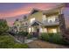 Charming yellow townhome exterior with stone accents and inviting front porch with beautiful dusk sky at 9434 Ashbury Cir # 204, Parker, CO 80134