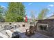 Outdoor patio with a fireplace, seating, and views of mature trees and blue skies at 1700 N Emerson St # 305, Denver, CO 80218
