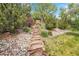 Landscaped backyard pathway featuring stone steps and lush plantings leading to a serene outdoor space at 3014 E Fremont Dr, Centennial, CO 80122