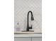 Close up of a modern matte black faucet with herringbone tile backsplash and light countertops at 1742 S Alcott St, Denver, CO 80219