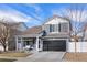 Charming two-story home with a covered porch and black garage door, set against a blue sky at 5017 Ceylon St, Denver, CO 80249