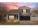 Charming two-story home with a covered porch and black garage door, set against a colorful sunset sky at 5017 Ceylon St, Denver, CO 80249