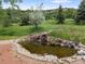 Backyard pond with small waterfall feature surrounded by lush landscape at 5979 Willow Springs Dr, Morrison, CO 80465
